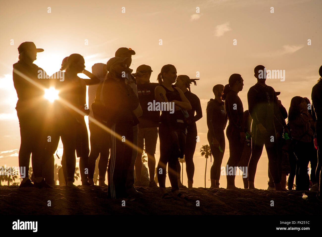 Come il sole sorge, a profilarsi folla si raduna in Newport Beach, CA, per guardare l inizio ufficiale del Nuoto parte di un evento di triathlon. (Foto di Spencer Grant) Foto Stock