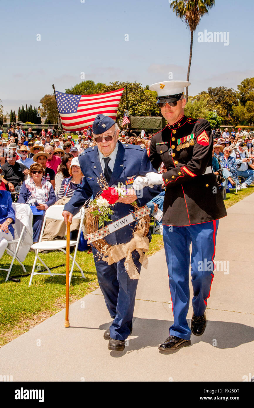 Un anziano US Air Force veterano porta una corona di fiori con l assistenza di un marine statunitense caporale durante il Memorial Day cerimonie presso una Costa Mesa, CA,cimitero. Foto Stock