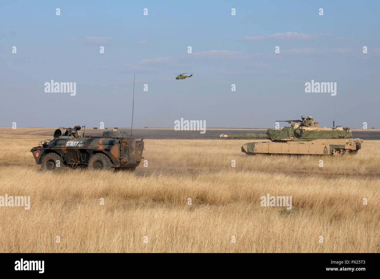 Un rumeno corazzato trasporto di personale e elicottero spostare in avanti come un M1A2 Abrams serbatoio da Charlie Company, 2° Battaglione, quinto reggimento di cavalleria, 1° Brigata corazzate contro la squadra, 1° Divisione di cavalleria veglia durante una spada di giustizia esercizio di campo a Smardan Area Formazione, Romania, 11 ott. 2018. I soldati del battaglione sono distribuiti in Europa a sostegno di Atlantic risolvere, il permanere di un esercizio di formazione tra la NATO e le forze americane. Foto Stock