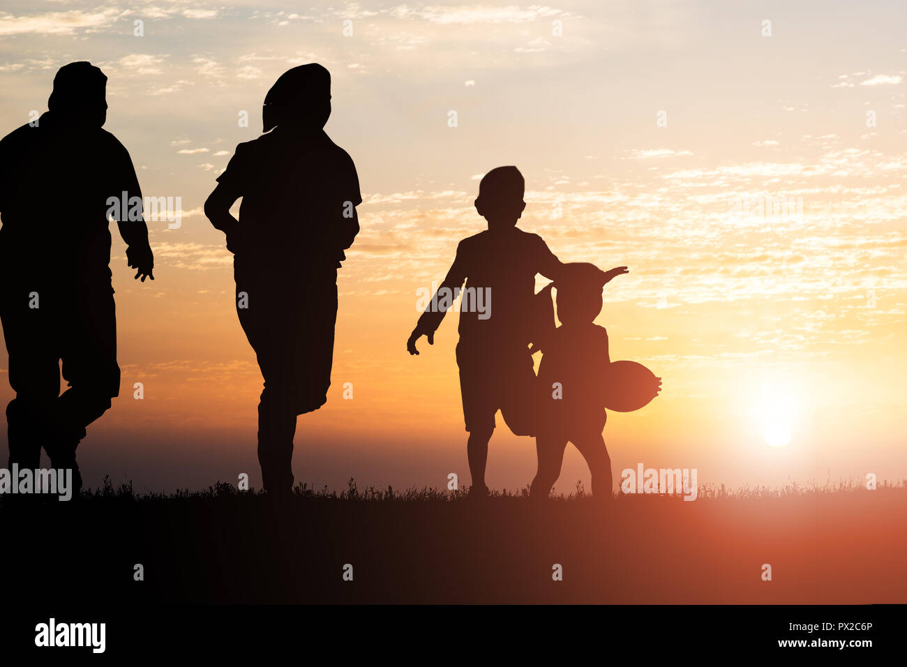 Silhouette di famiglia in esecuzione in Park contro il cielo al tramonto Foto Stock
