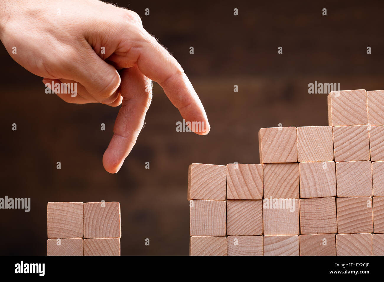 Close-up di una persona a passo sul dito impilati i blocchi in legno Foto Stock