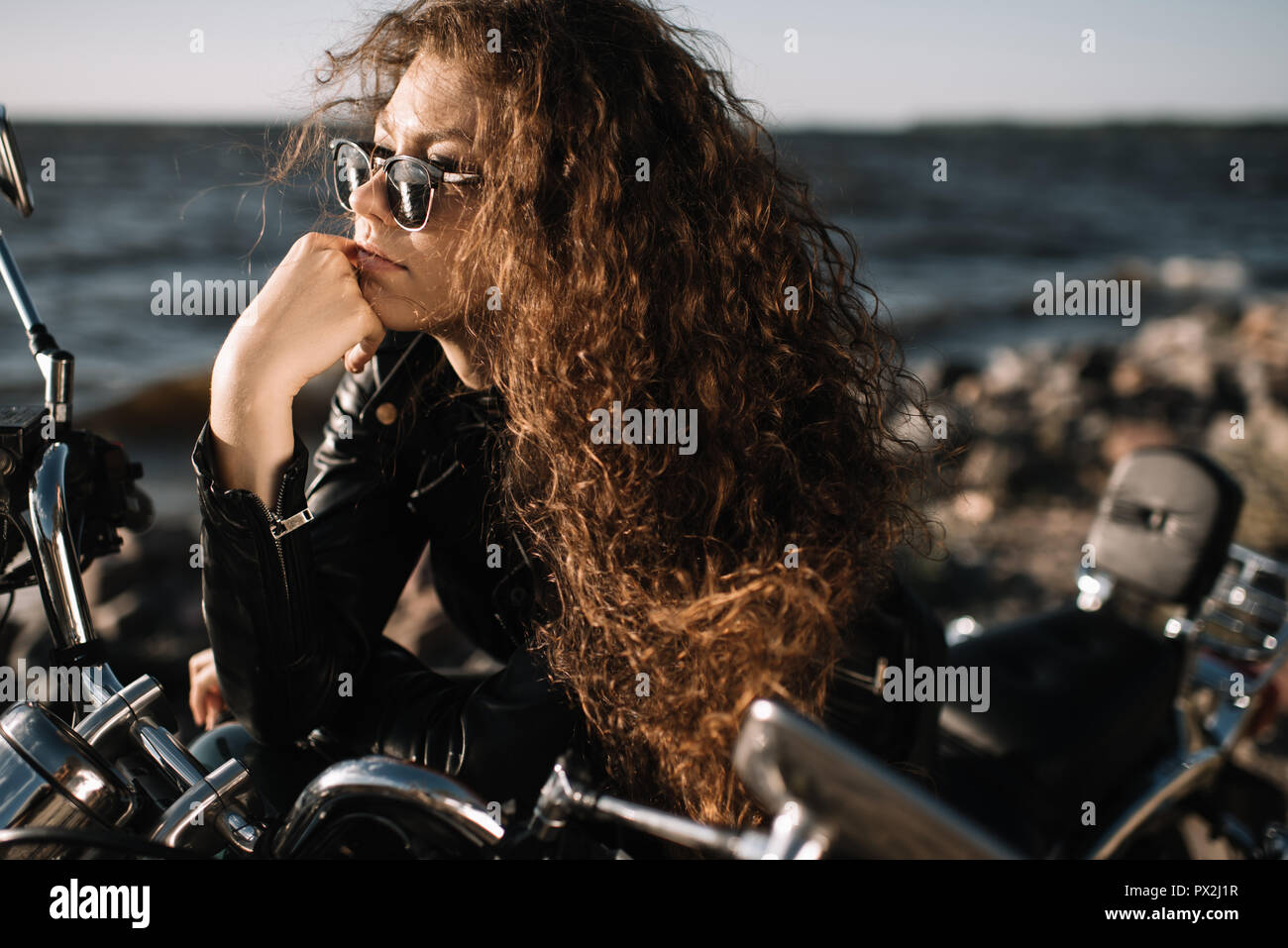 Attraente femmina ricci biker in occhiali da sole seduto sulla moto Foto  stock - Alamy