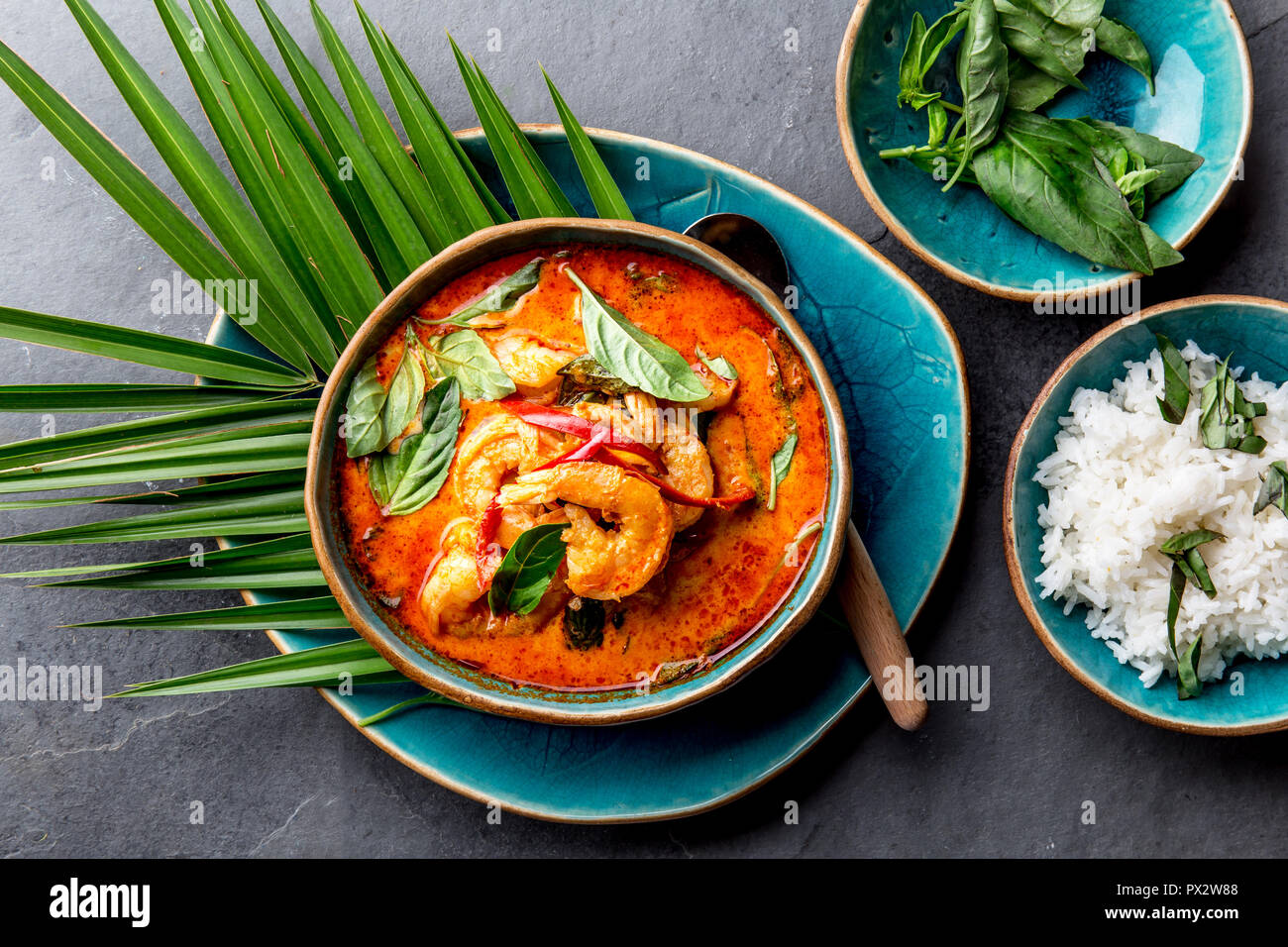 Gamberetti THAI RED curry. Thailandia tradizione rosso zuppa di curry con gamberi  e latte di cocco. Panaeng Curry nella piastra di colore blu su sfondo  grigio Foto stock - Alamy