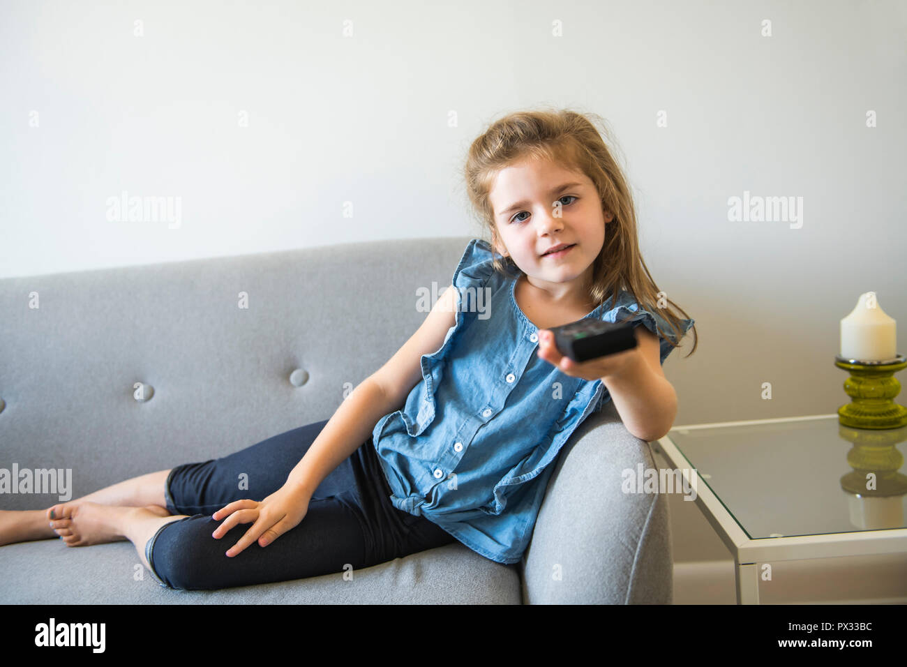 Carino bambina guarda la TV sul divano sul divano Foto Stock