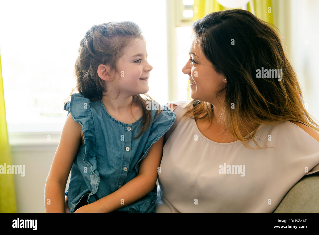 Madre e figlia avente un grande tempo sul divano Foto Stock