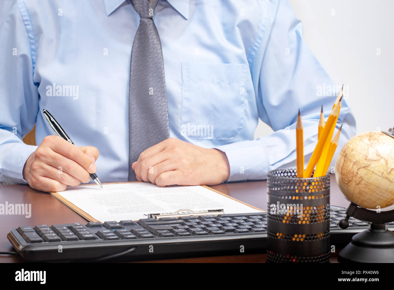 Imprenditore seduto alla scrivania in ufficio la firma di un contratto con shallow focus sulla firma Foto Stock