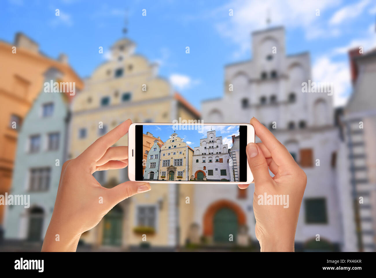 Un turista è scattare una foto del complesso edilizio di vecchi edifici - i tre fratelli - Riga, Lettonia su un telefono cellulare Foto Stock