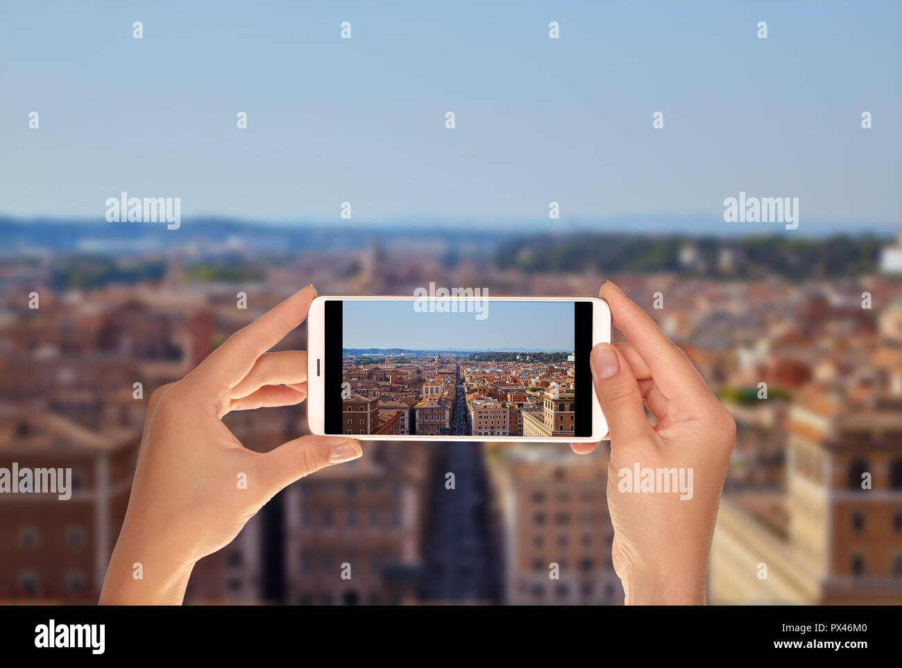 Un turista è scattare una foto della vista panoramica di Roma dal ponte di osservazione sul monumento di Vittorio Emanuele su un telefono cellulare Foto Stock