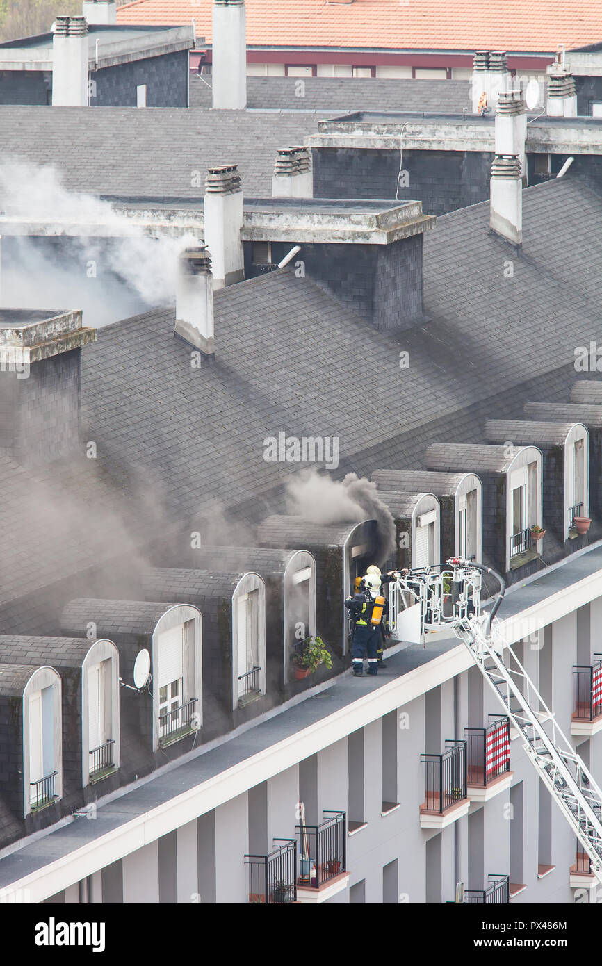 I vigili del fuoco su una scala estinguere un incendio Foto Stock