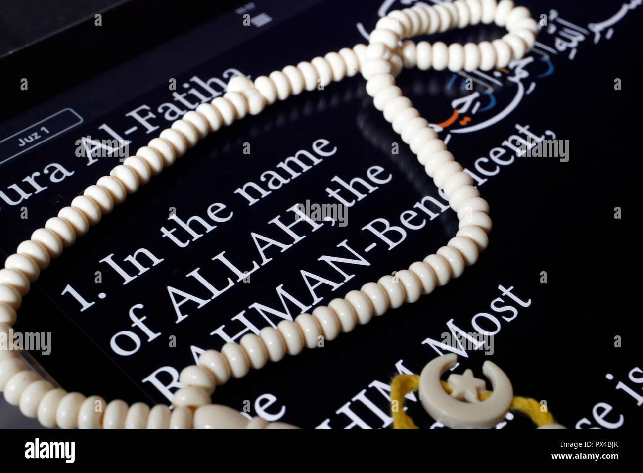 Corano elettronico su un tablet e grani di preghiera. Traduttore inglese. Prima pagina : nel nome di Allah. Foto Stock