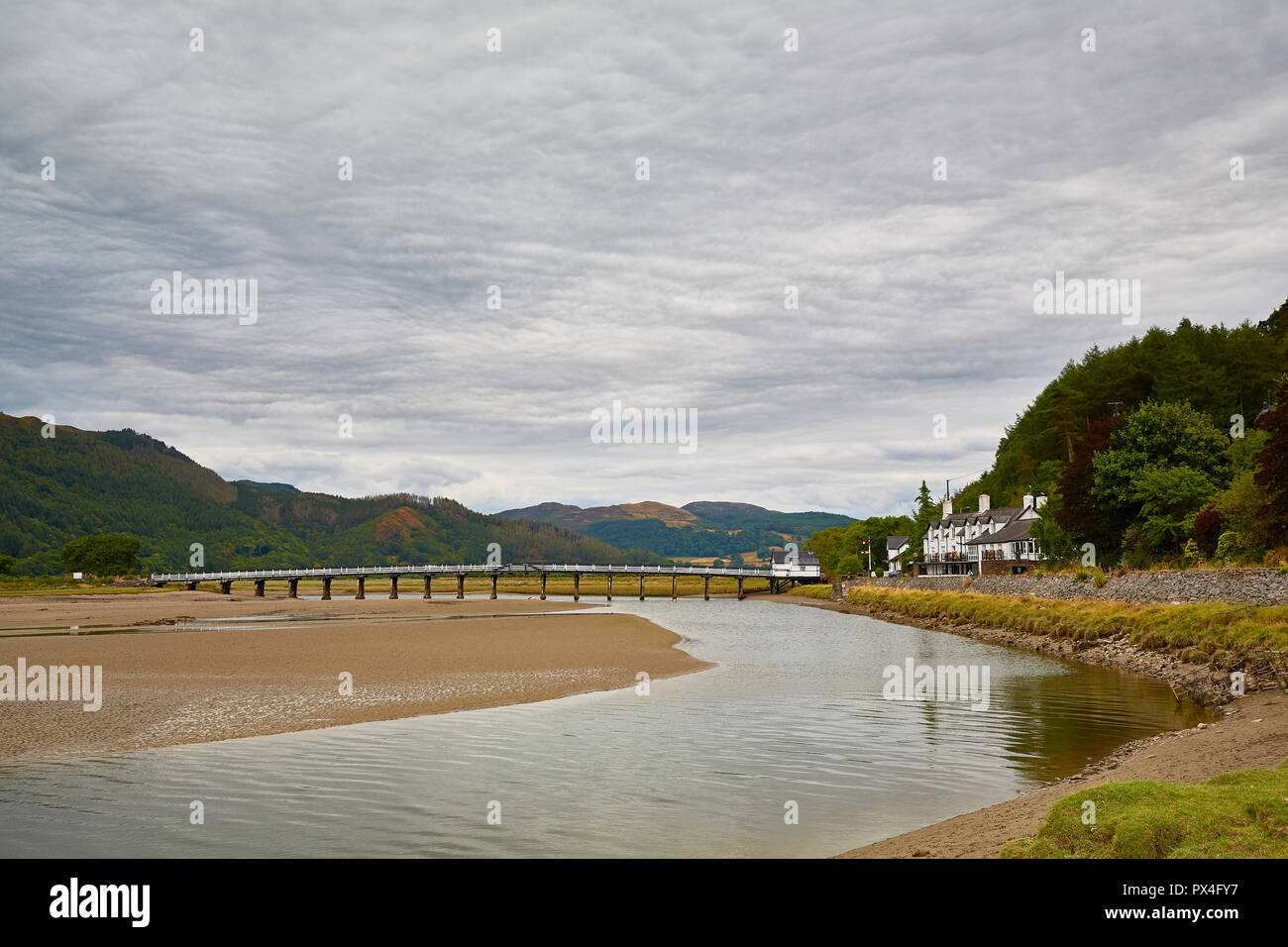 Vista del Penmaenpool ponte che attraversa il Afon Mawddach estuary a bassa marea con il ponte a pedaggio House e il George III Hotel vicino a Caernarfon, Galles Foto Stock