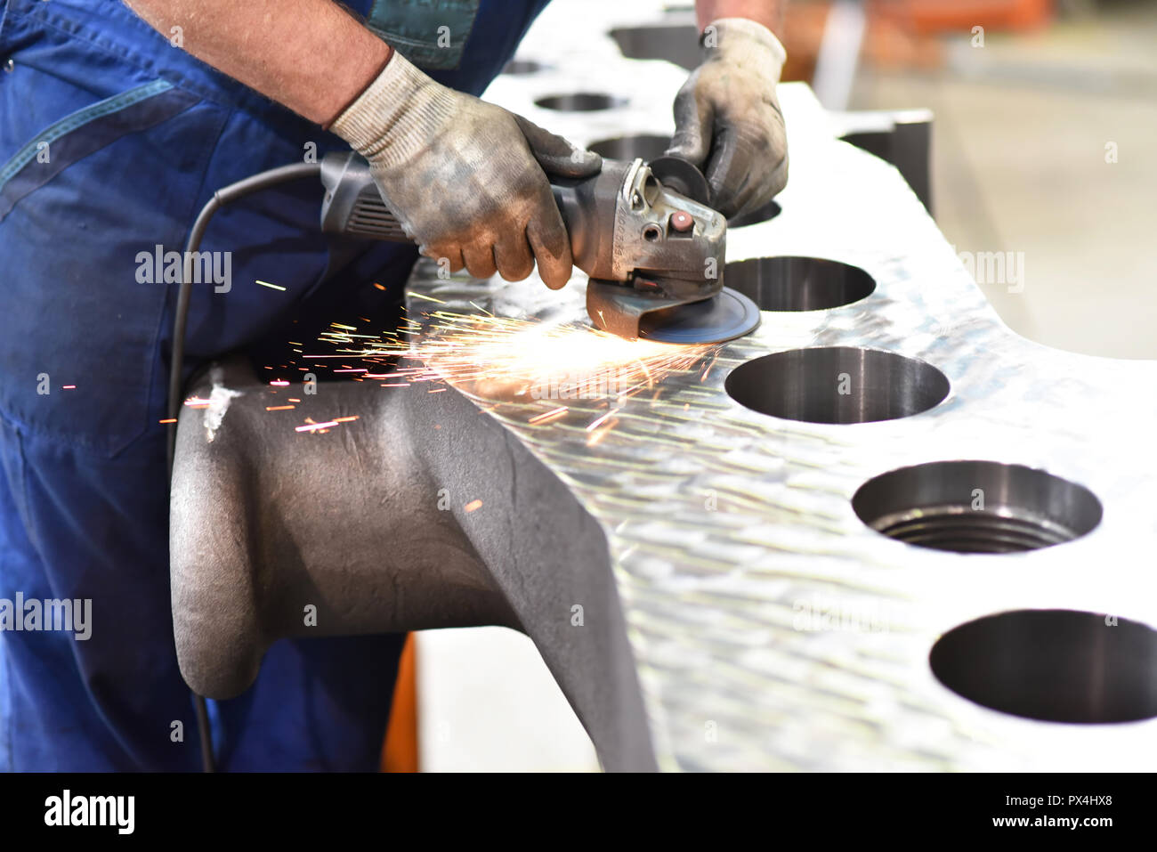 Ingegneria meccanica lavoratore macina in metallo con la macchina durante la fase di costruzione della turbina a gas Foto Stock