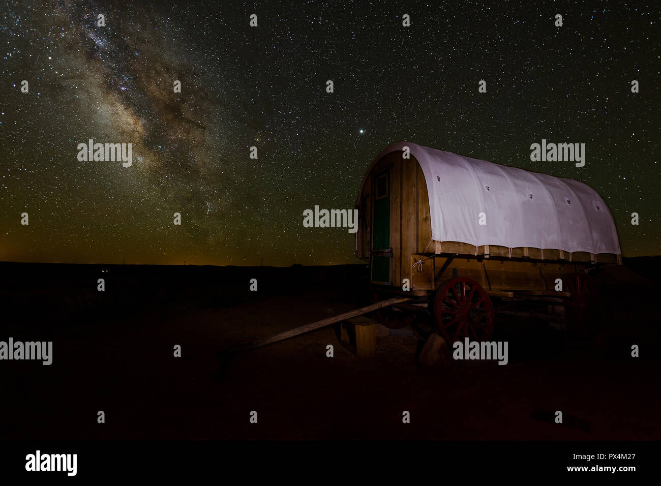 In Arizona, Stati Uniti d'America. Viste mozzafiato della Via Lattea oltre il deserto dell'Arizona campeggio, con un colono-style carro in primo piano. Foto Stock