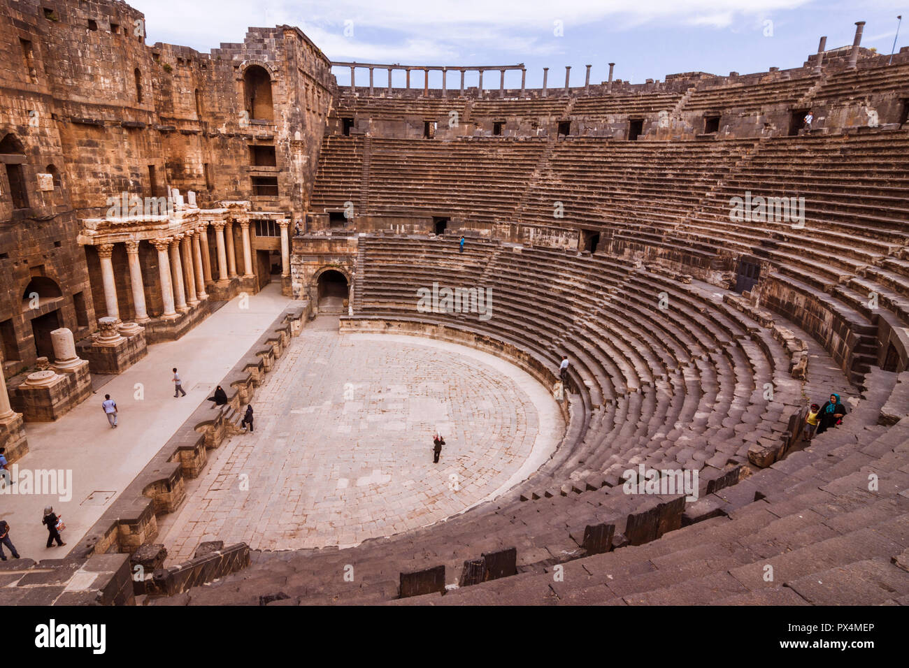 Bosra, Siria : visitatori presso le rovine del II secolo D.C. Teatro romano di Bosra in seguito completamente racchiuso da un Ayyūbid fortezza medievale. Con il sedile di guida Foto Stock