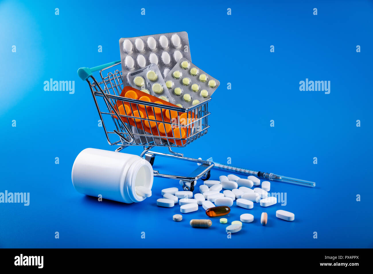 Carrello pieno di farmaco e pillole medicinali su sfondo blu Foto Stock