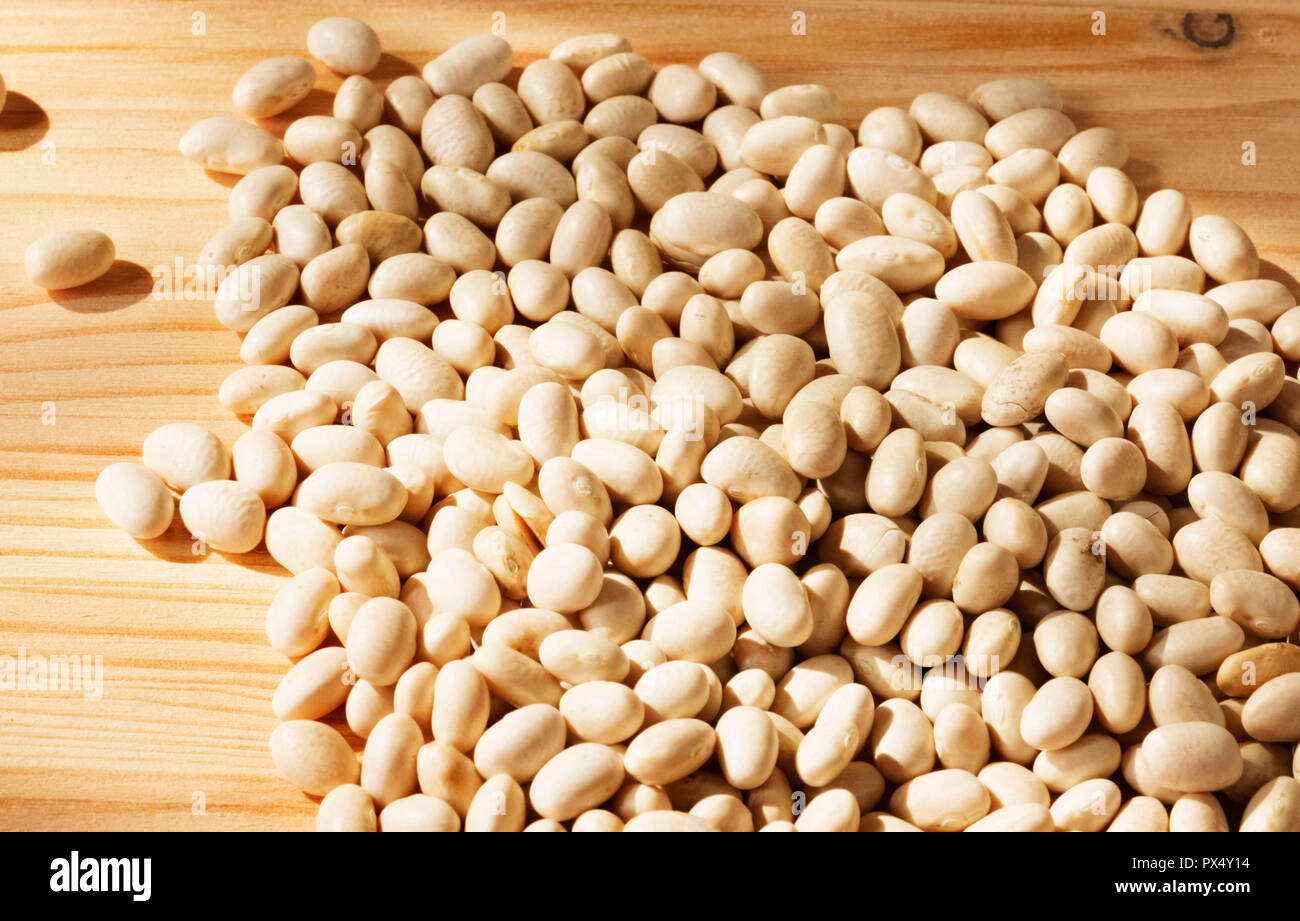 Un brillante pila di fagioli bianchi su uno sfondo di legno , studio shot , vista dall'alto , alto contrasto Foto Stock