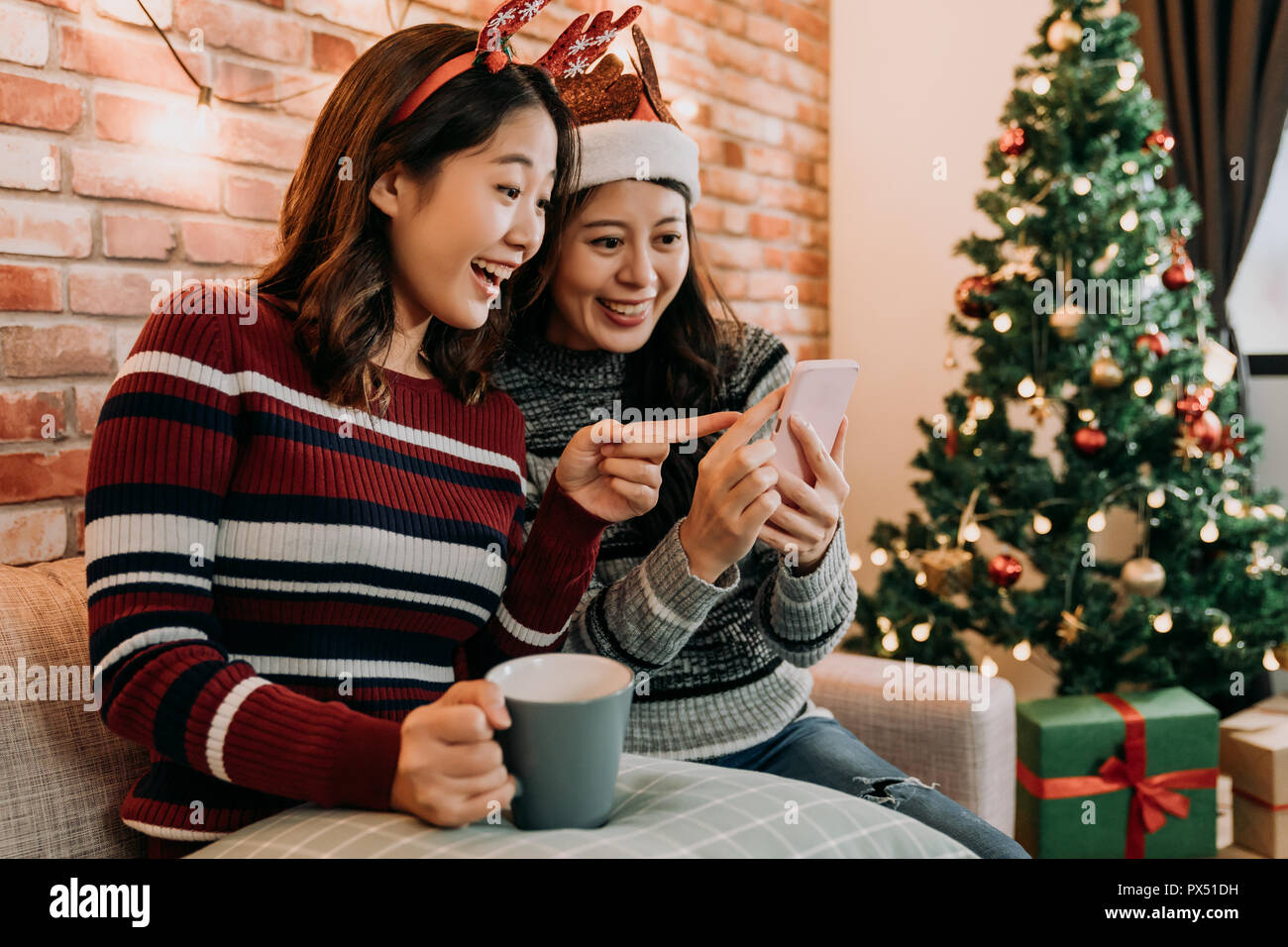 Migliori amici con santa hat e cervi sono lo shopping online a casa con lo smartphone. grande vendita di Natale in dicembre. sorpreso puntando alla sorprendente pr Foto Stock