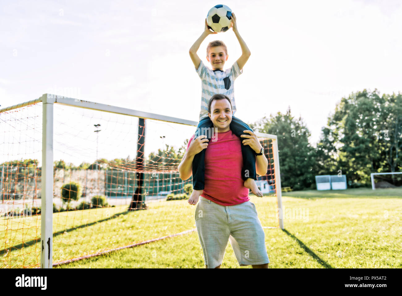 Uomo con bambini che giocano a calcio al di fuori sul campo Foto Stock