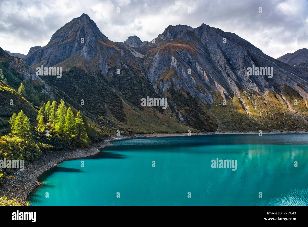 Fantastici colori di acqua sul lago Morasco con l'ombra di piante e riflessa e le montagne sullo sfondo nella stagione autunnale Foto Stock