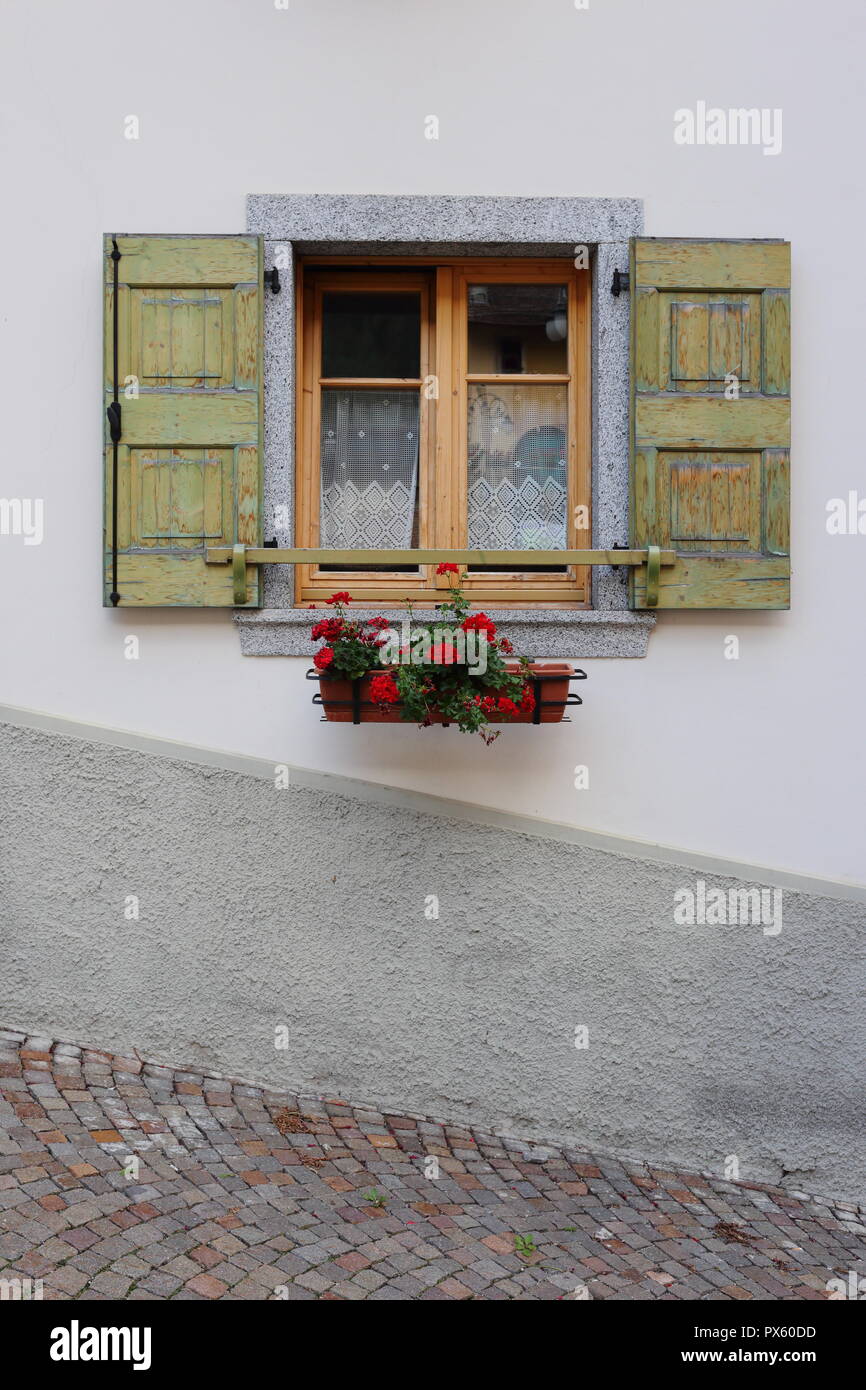 Vecchia finestra con tende di pizzo, decorato con fiori in Trentino, Italia. Foto Stock