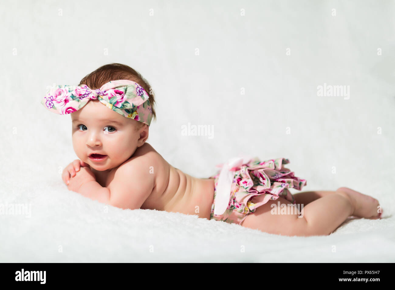 Bellissima bambina in biancheria da letto bianca a casa aspetto piacevole Foto Stock