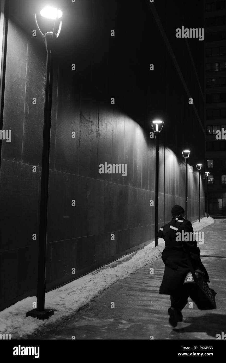 Bianco e nero colpo di uomo a camminare giù per una strada di notte, Toronto, Ontario, Canada. Foto Stock