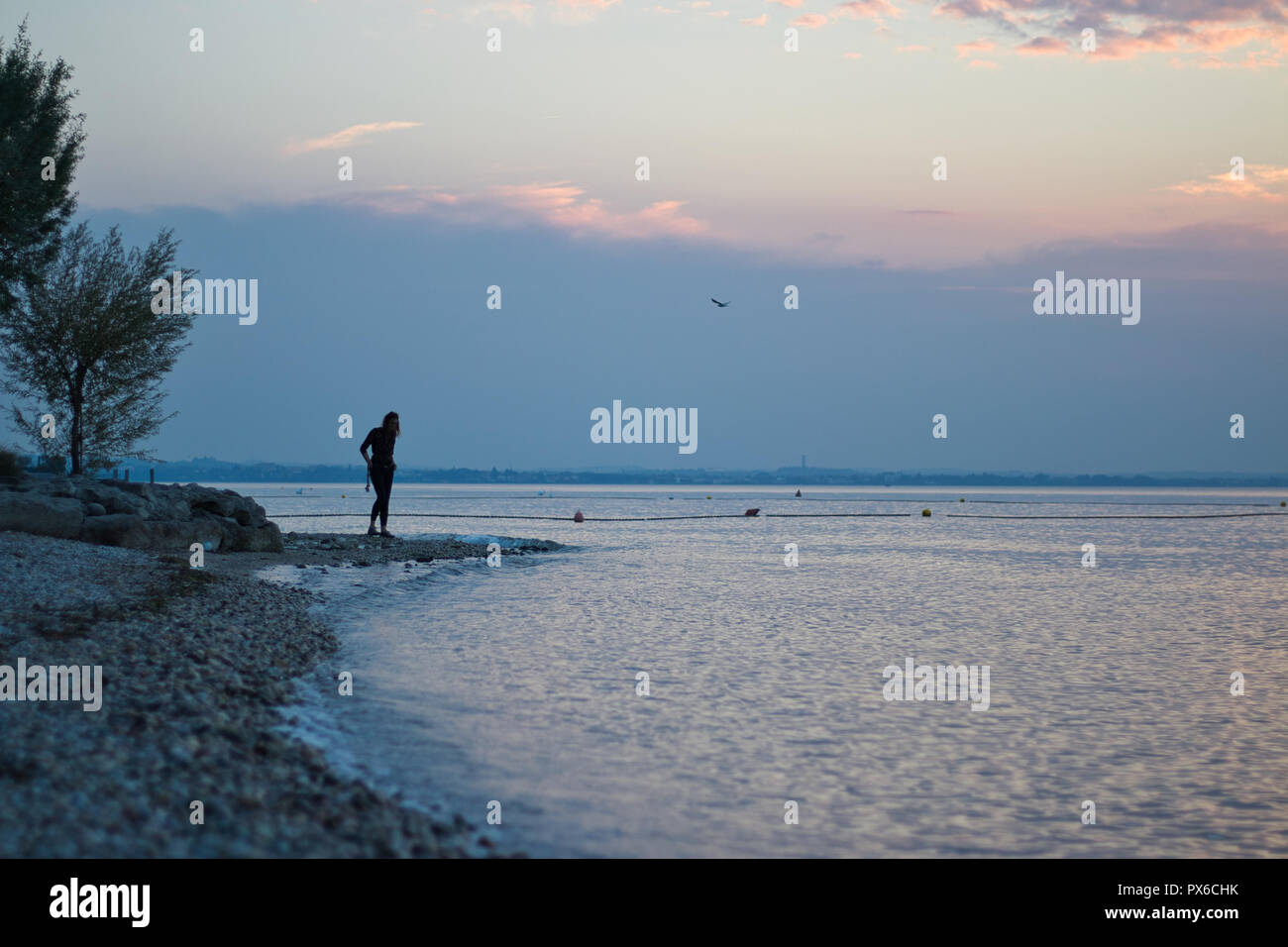 Donna in spiaggia durante il tramonto Foto Stock