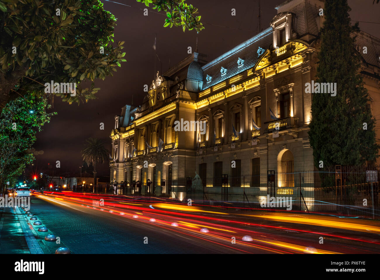 Edificio pubblico, la sede del governo della provincia di Jujuy, Argentina. Si vede incorniciato dalle cime degli alberi e le tracce di una luce di passaggio vehicl Foto Stock