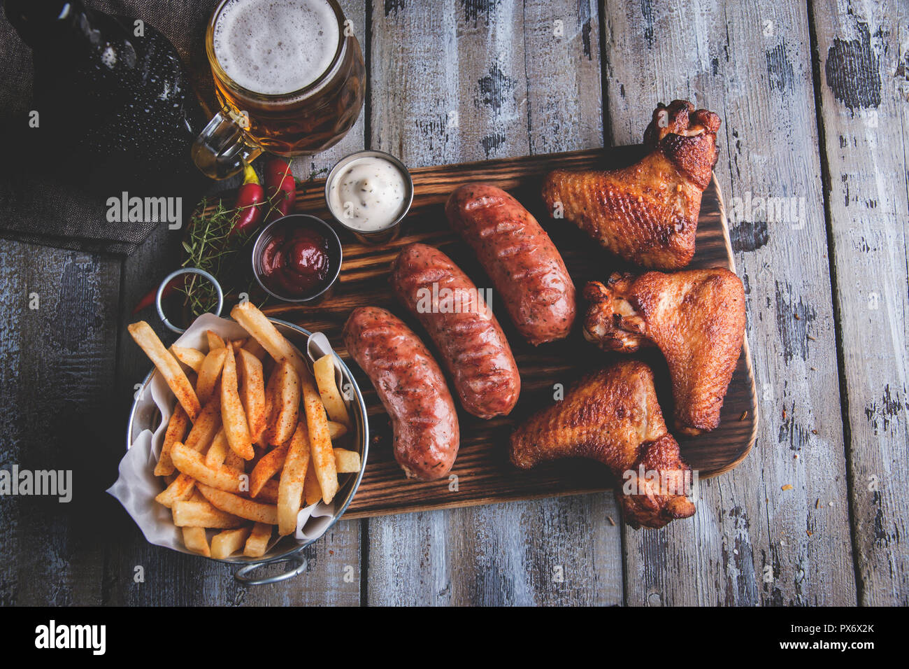 Alette di pollo fritte,salsicce alla griglia, patate fritte, dadi, bianco e salsa rossa. cibo alla birra Foto Stock