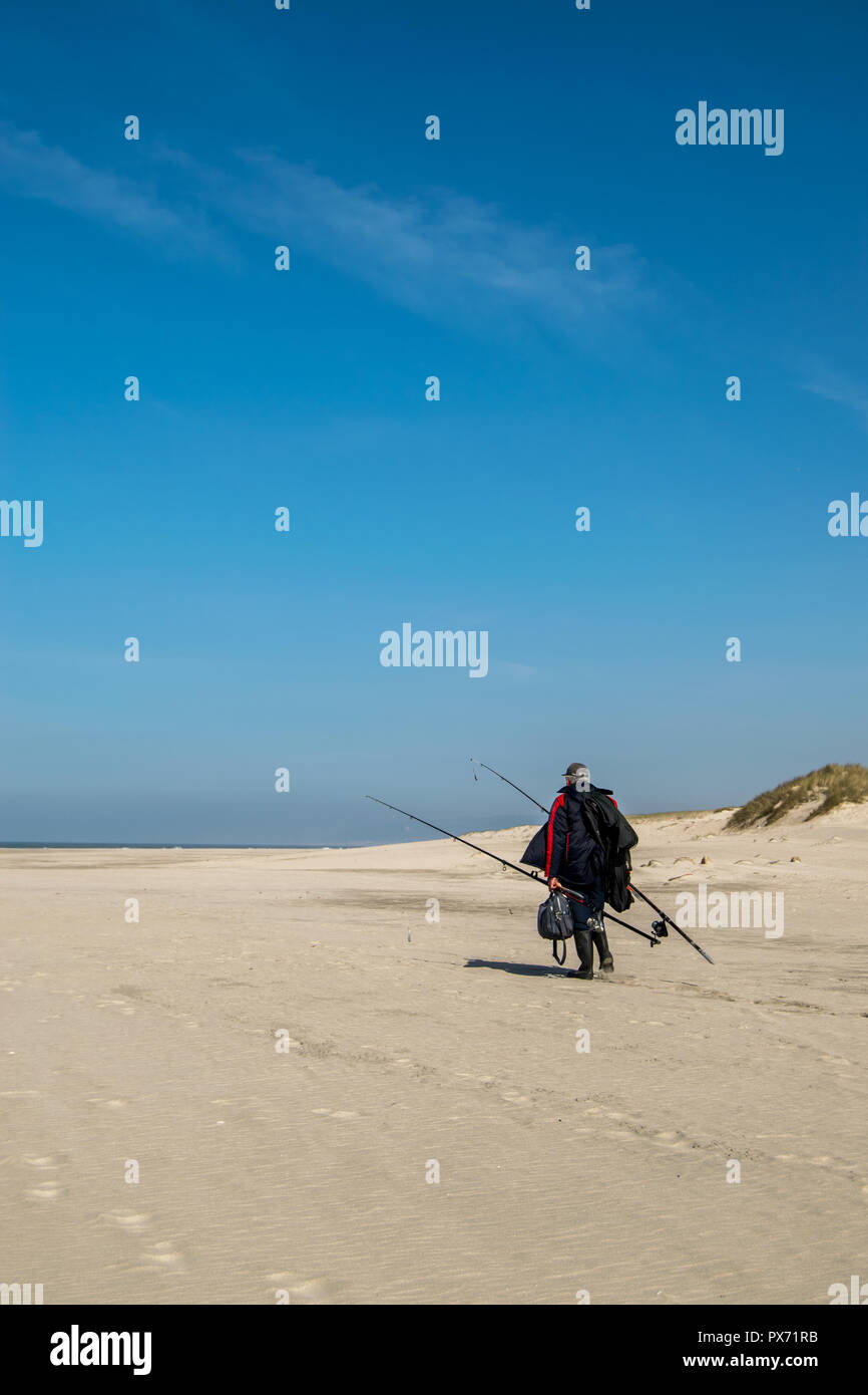 Il pescatore che cammina sulla spiaggia con l'attrezzatura è a Ofir playa, Portogallo Foto Stock