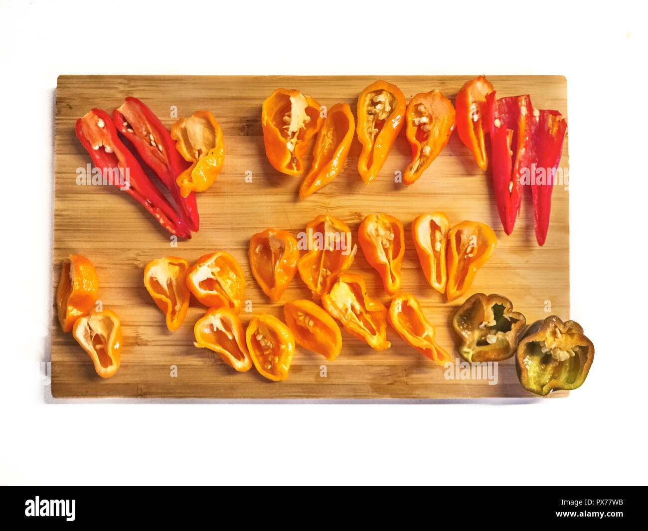 Inquadratura di un mix di Habanero, Naga Morich e Cayenna peperoni tagliati a fettine su un tagliere Foto Stock