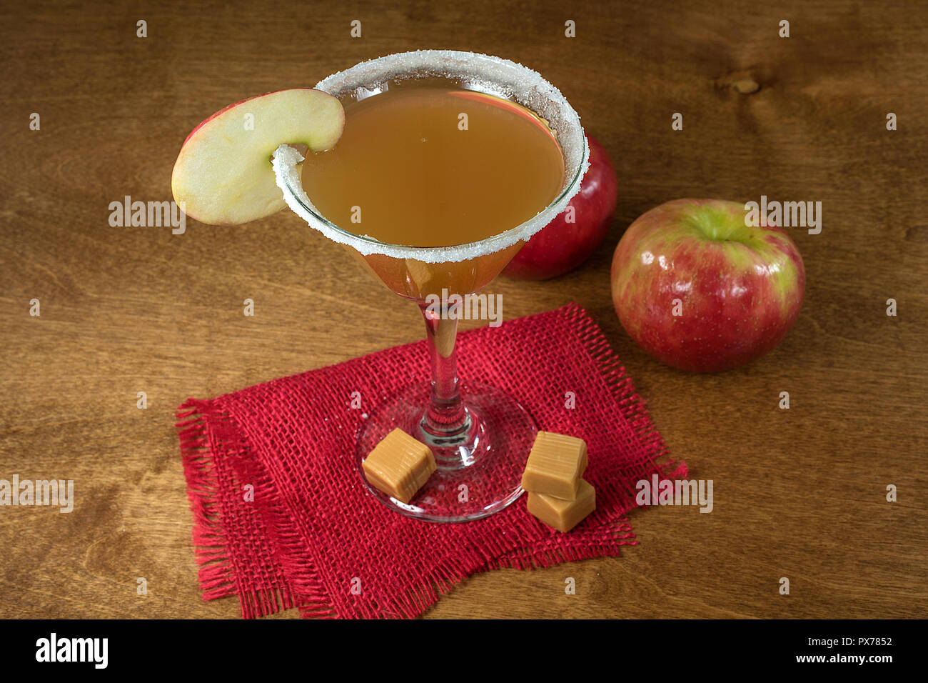 Sidro di mela martini cocktail con apple slice guarnire e caramella sulla tela rossa Foto Stock