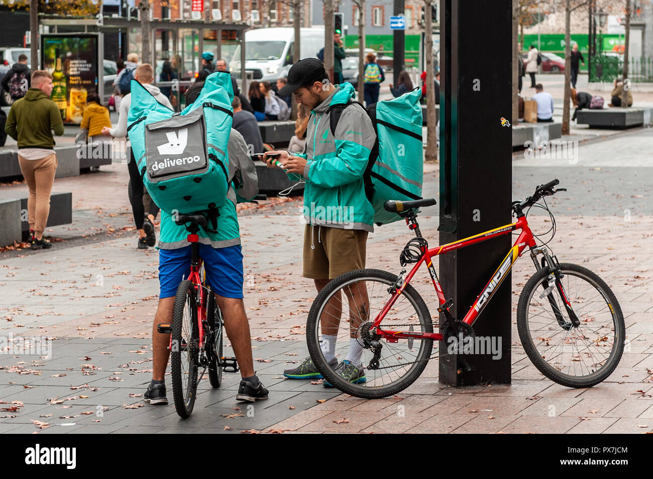 I piloti Deliveroo attendere di ricevere i loro ordini su Grand Parade, Cork, Irlanda. Foto Stock