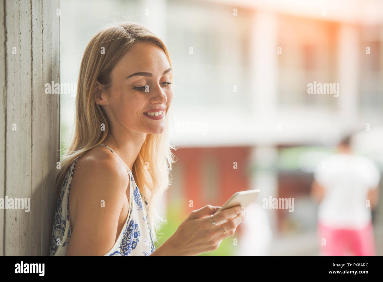 Bella giovane donna è l'utilizzo di un'app nel suo smart phone dispositivo per leggere e-mail, ricezione di testo, scrivi messaggio o navigare in internet mentre all'aperto Foto Stock