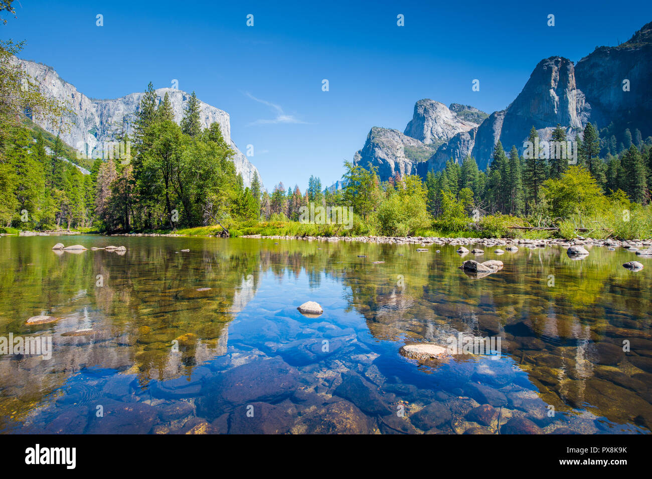 Visualizzazione classica di scenic Yosemite Valley con il famoso El Capitan arrampicata su roccia vertice e idilliaco fiume Merced in una giornata di sole con cielo blu e nuvole Foto Stock