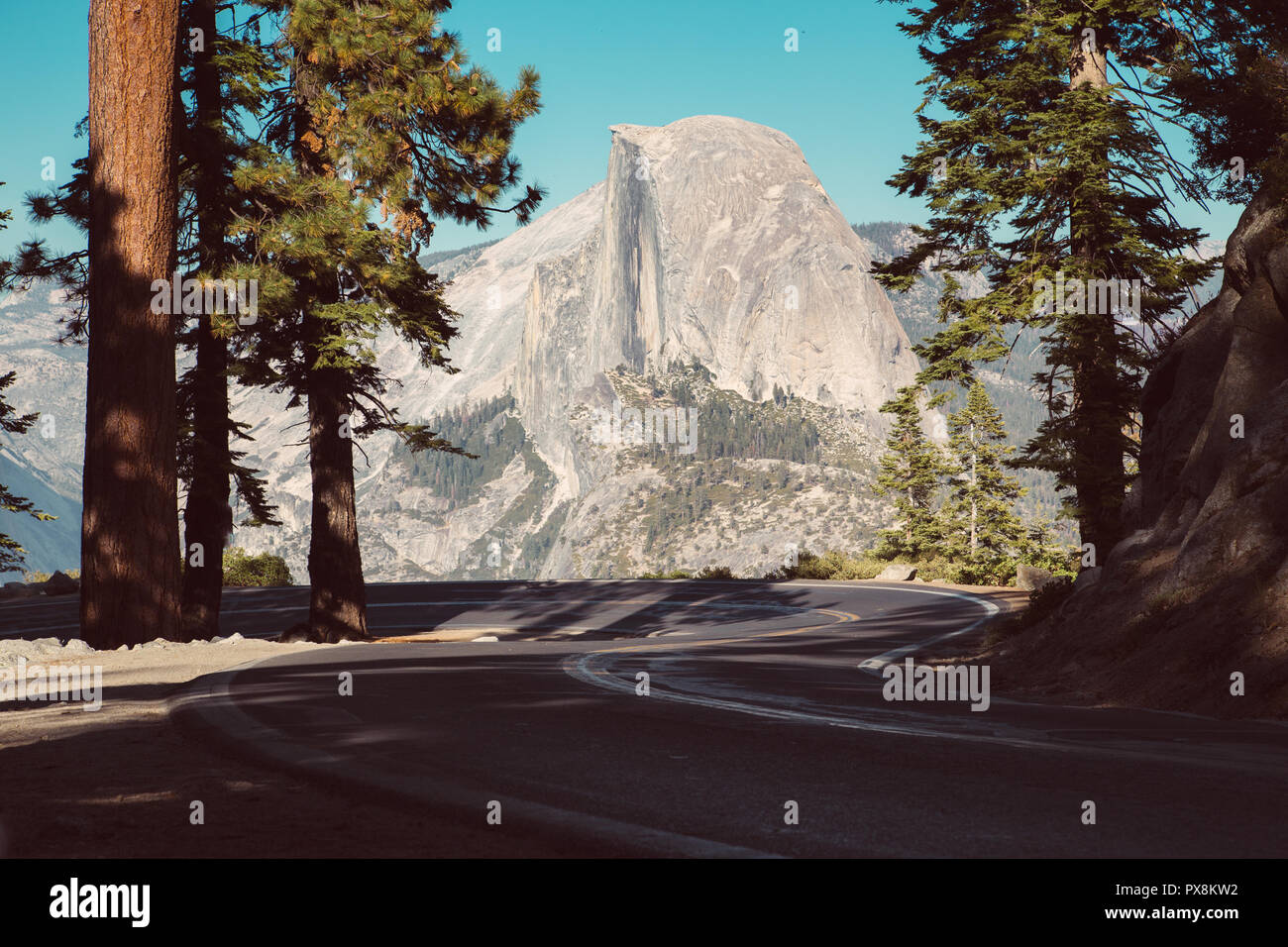 Bellissima vista di avvolgimento di Glacier Point Road con il famoso Half Dome vertice di golden luce della sera al tramonto, Yosemite National Park, California, Stati Uniti d'America Foto Stock