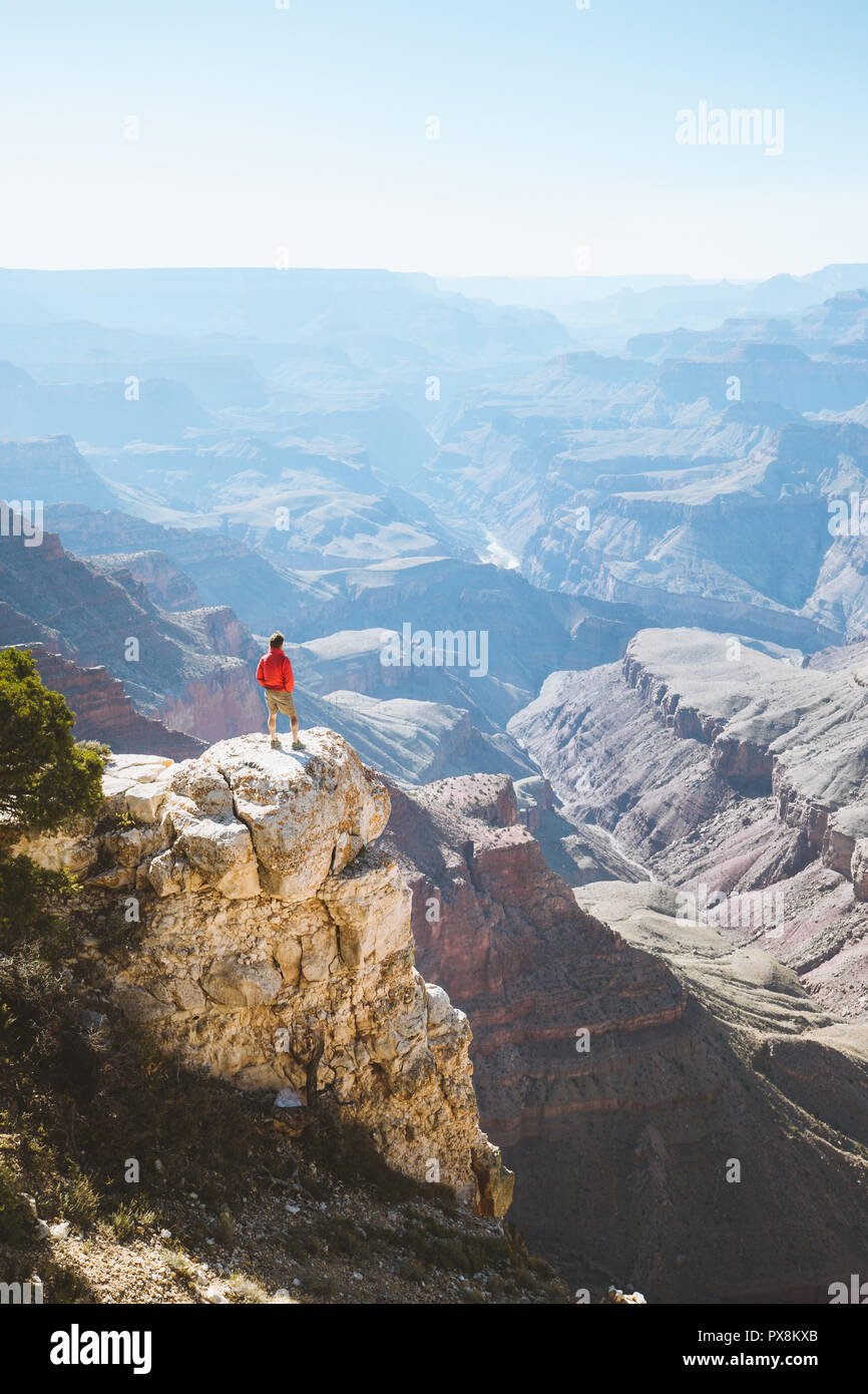 Un maschio di un escursionista è in piedi su una ripida scogliera prendendo in una favolosa vista sul famoso Grand Canyon in una bella giornata di sole con cielo blu in estate, Grand Foto Stock