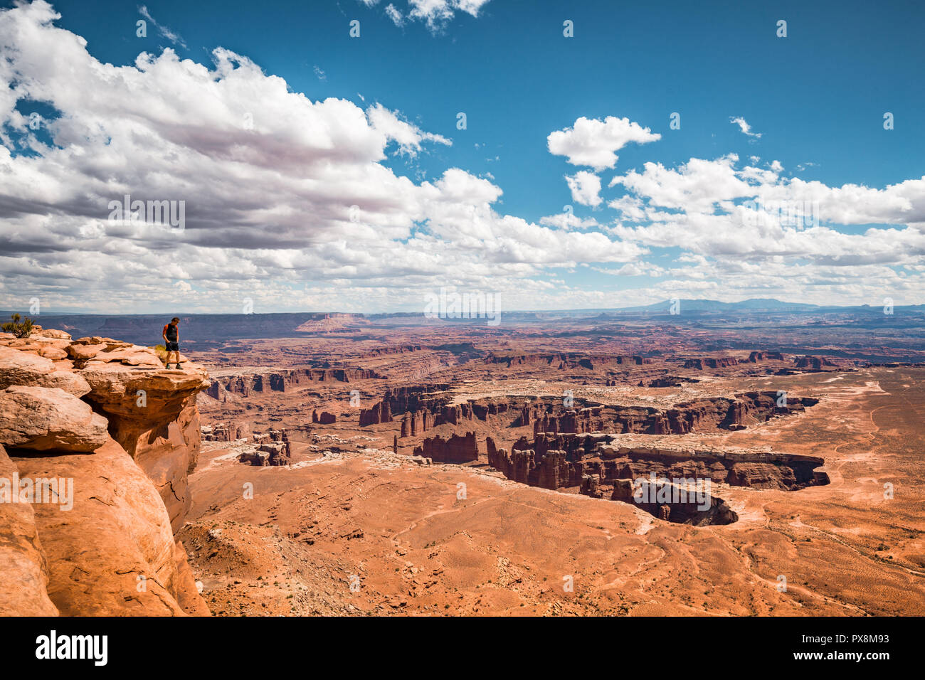 Un maschio di un escursionista è in piedi sul bordo di una scogliera godendo di una drammatica si affacciano di paesaggio panoramico nel bellissimo Parco Nazionale di Canyonlands, Utah, Stati Uniti d'America Foto Stock