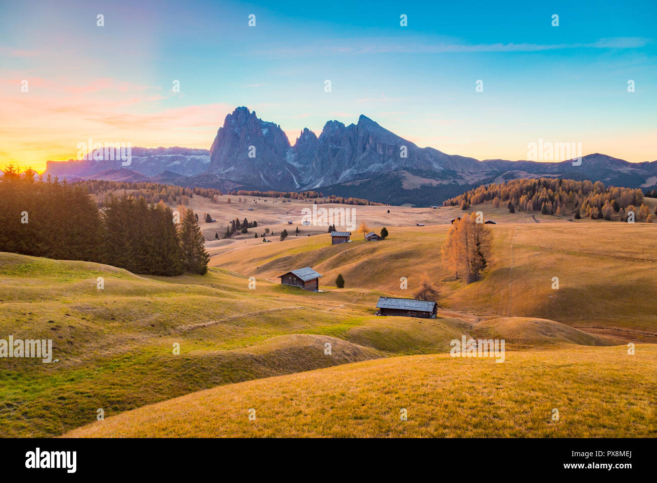 Bellissima vista del legno tradizionale chalet di montagna su SCENIC Alpe di Siusi con il famoso Sassolungo picchi di montagna in background in golden mattina Foto Stock