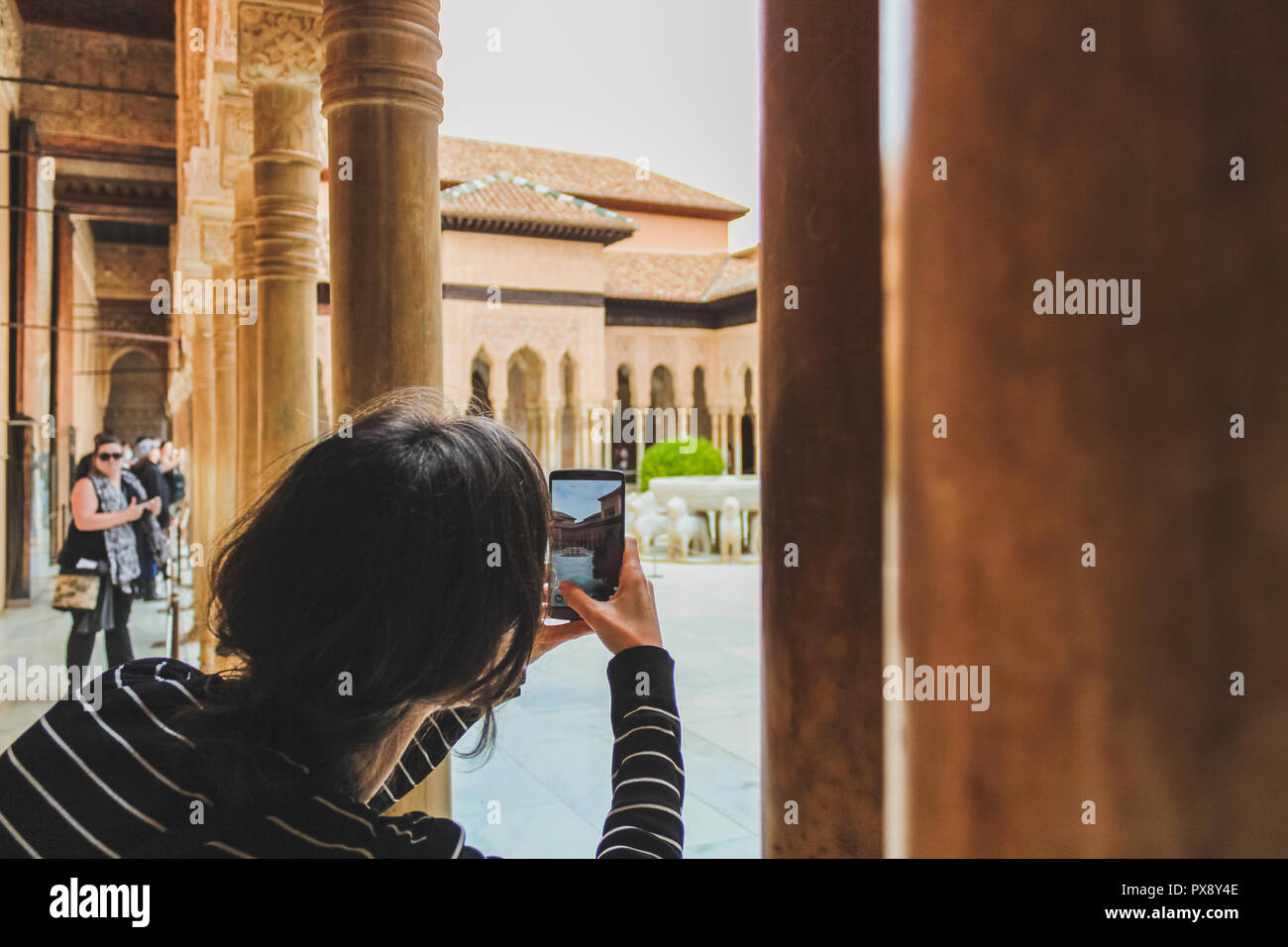 La fontana dei leoni, il famoso marmo moresco cortile con fontana a Granada Spagna. Giovane ragazza turistica di scattare una foto Foto Stock