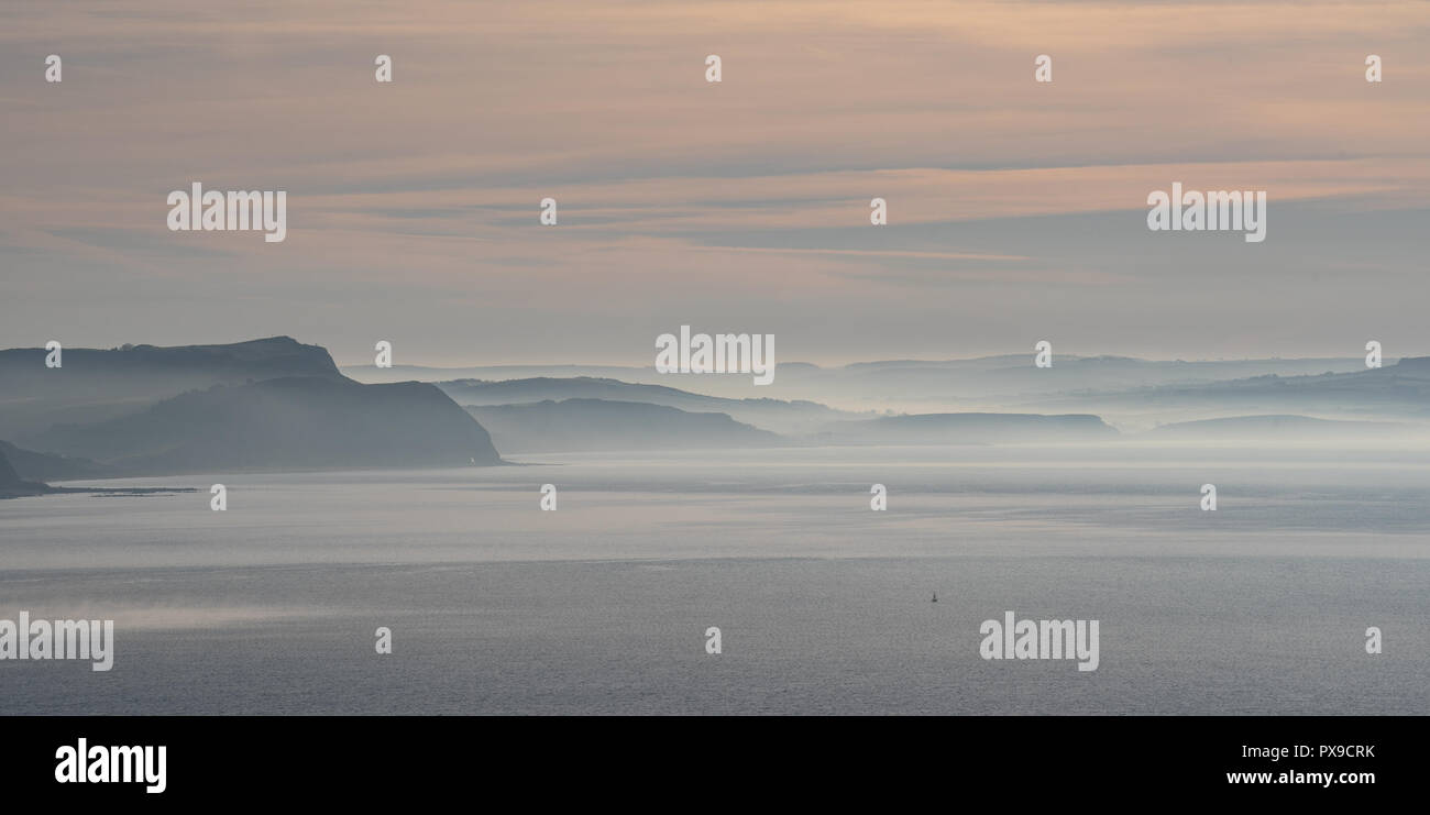 Charmouth, Dorset, Regno Unito. Xx Ottobre 2018. Meteo REGNO UNITO: Early Morning mist sorge oltre il Golden Cap e le scogliere lungo la Jurassic Coast vicino a Charmouth. Credito: Celia McMahon/Alamy Live News Foto Stock