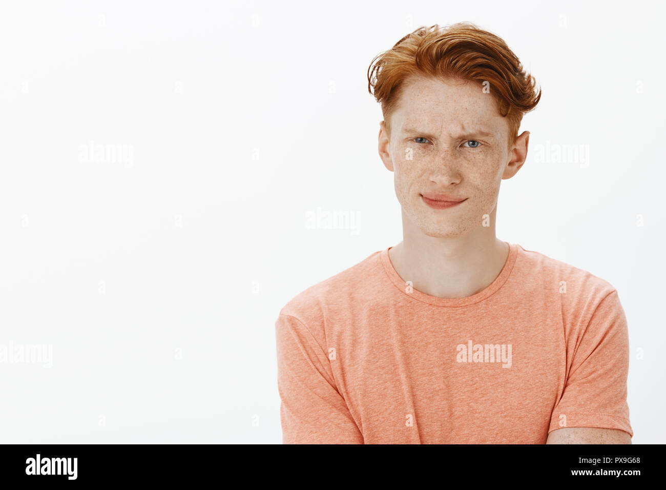 Dubbia idea, io non lo supportano. Ritratto di orinato sicuri e esitando carino redhead maschio con lentiggini, accigliata e smirking da disappontment, esprimendo antipatia su sfondo grigio Foto Stock