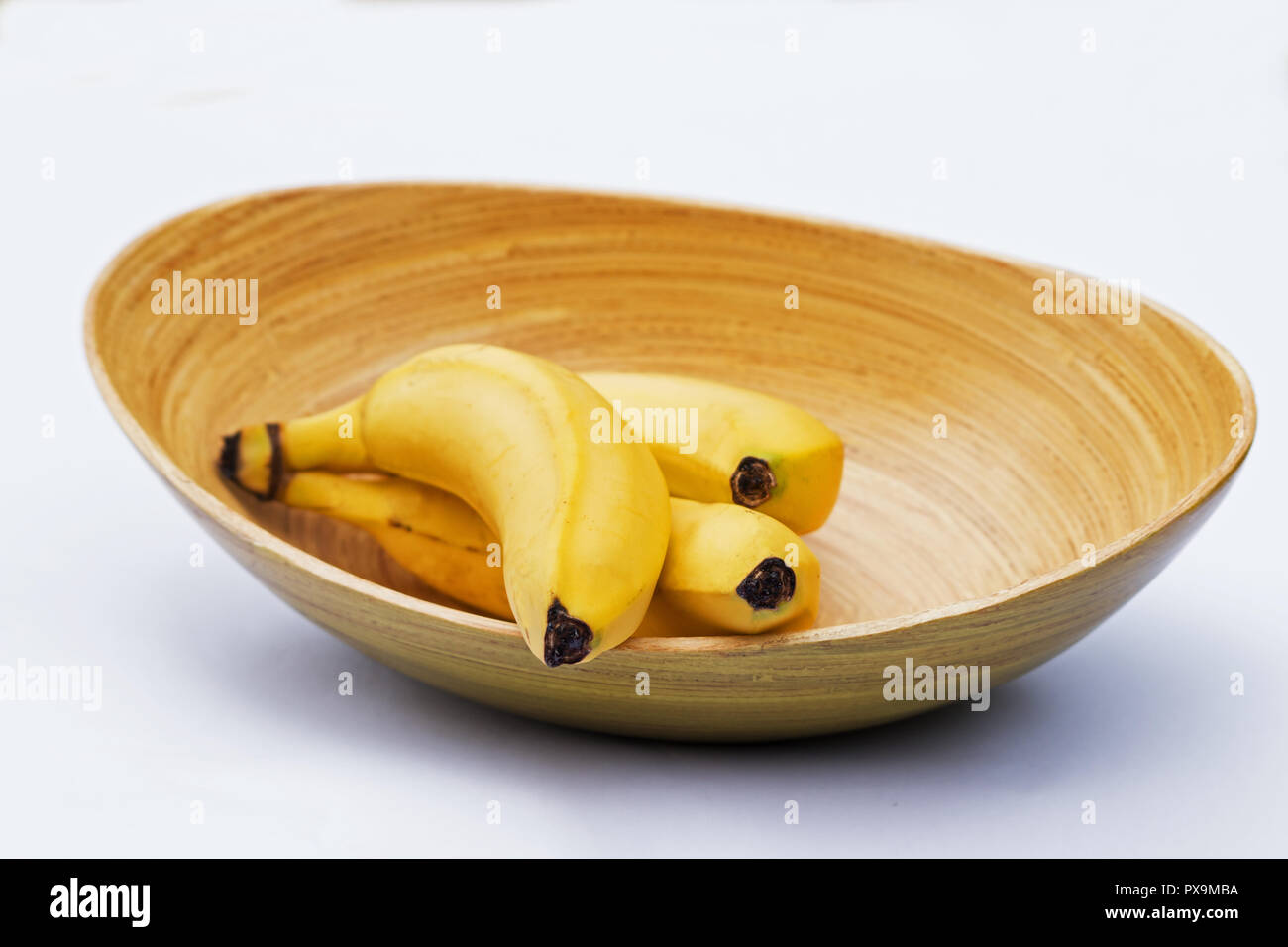 Le banane fresche in una ciotola su sfondo bianco Foto Stock