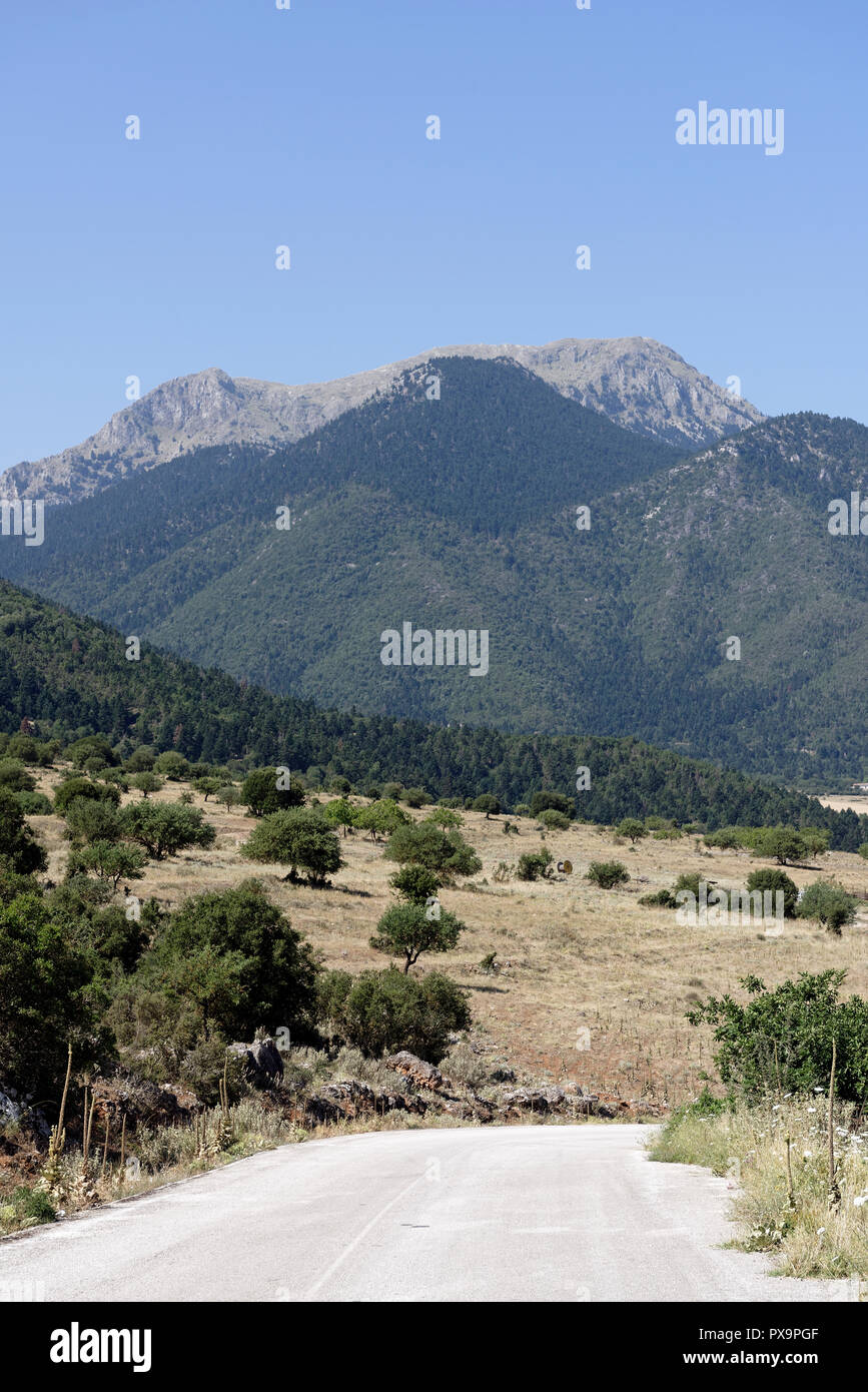 Strada che costeggia il lago di Stymphalia e circondato da paesaggi montuosi, Peloponneso e Grecia. Famoso nel mito come il sito dove Eracle uccise il ma Foto Stock