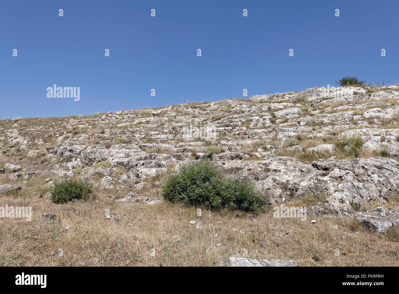 Vista dei resti del teatro con sedili tagliati nella roccia calcarea. La città bassa, antica Stymphalos. Stymphalia. Peloponneso. La Grecia. Foto Stock