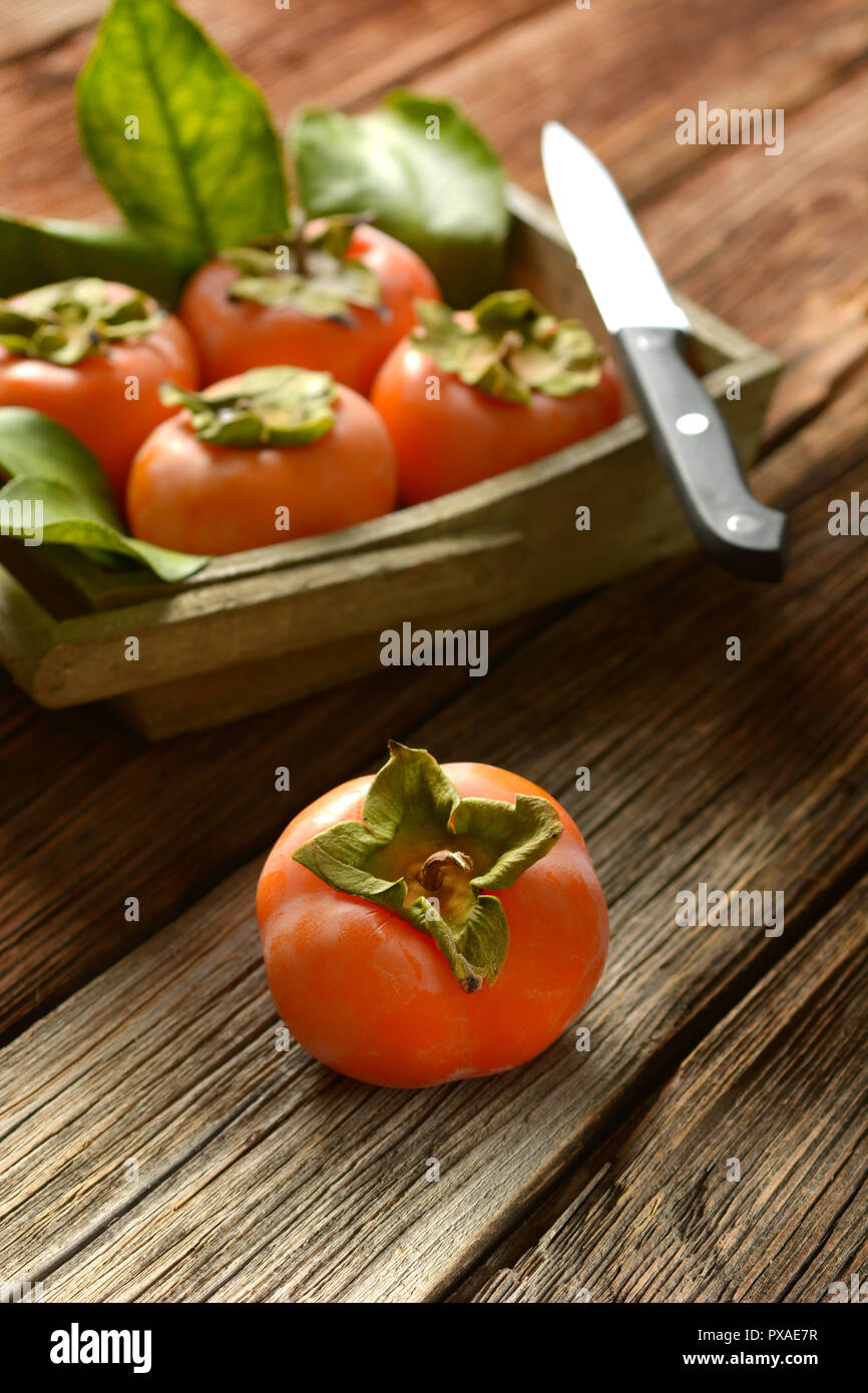 Pila di cachi maturi sul tavolo di legno - primo piano Foto Stock