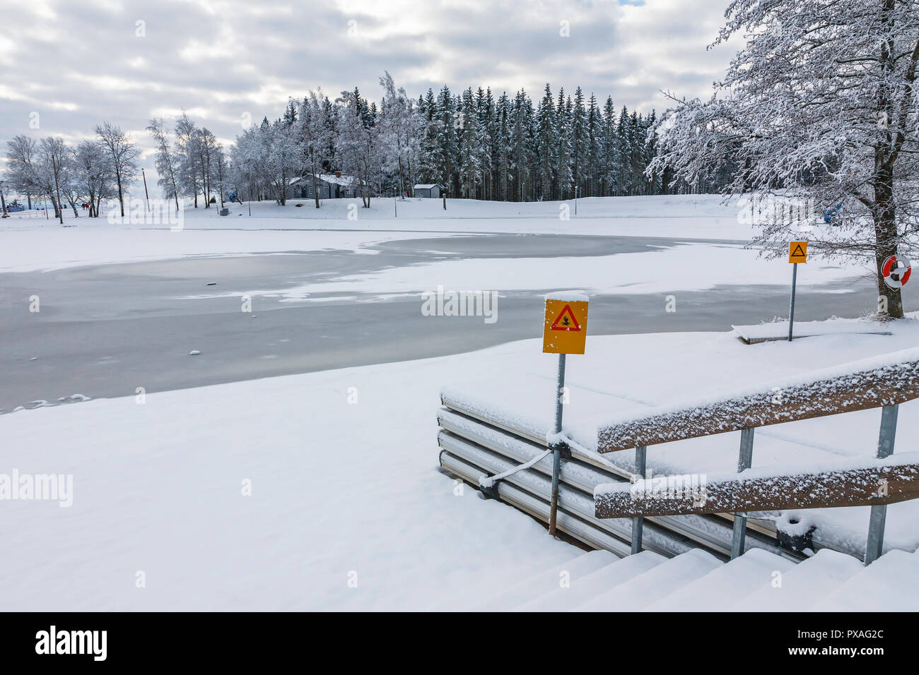 Coperte di ghiaccio sul lago con un cartello di avvertimento per il ghiaccio sottile Foto Stock