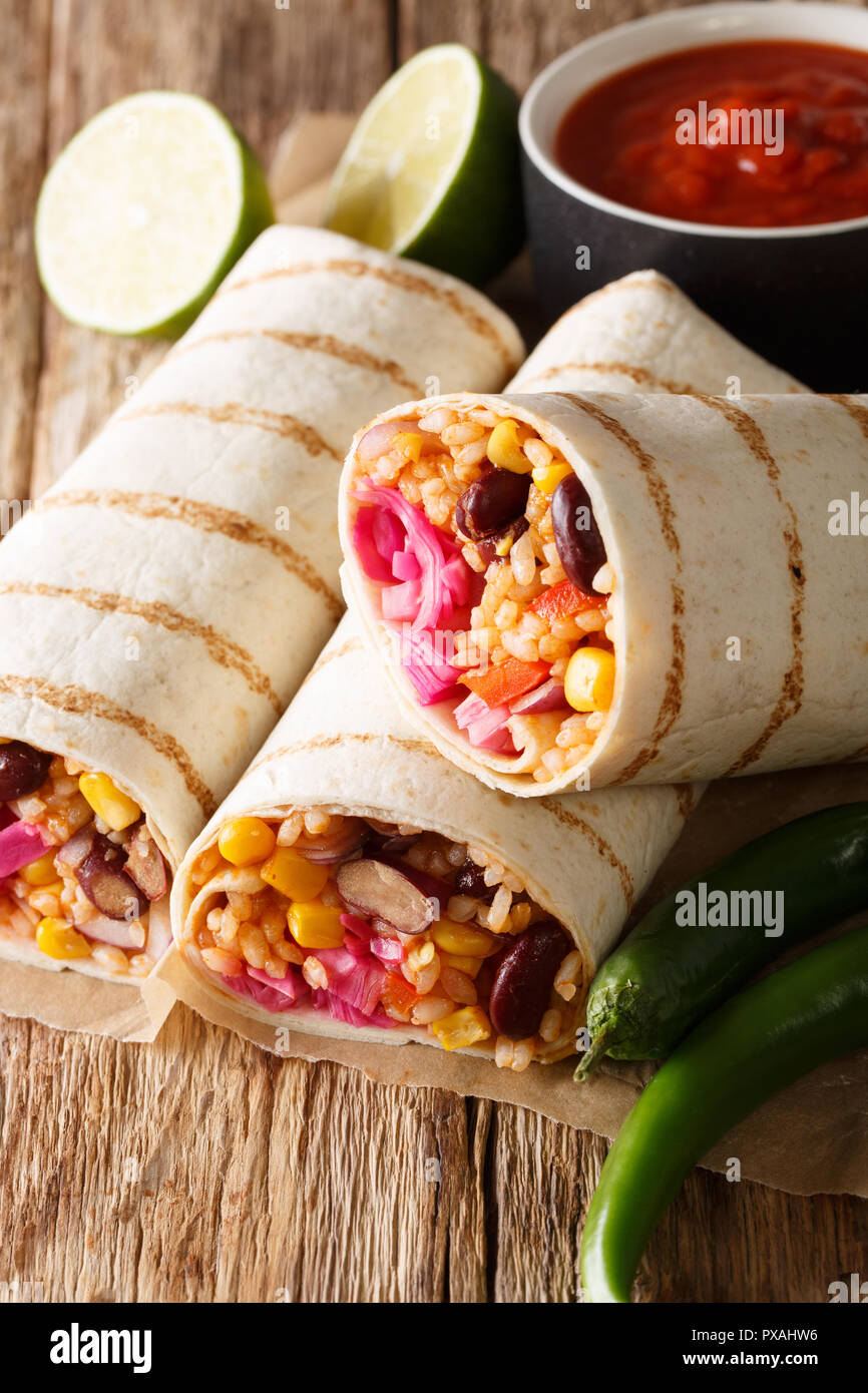 Burrito vegetariano ripieni di riso e verdure serviti con salsa di pomodoro closeup sul piano verticale. Foto Stock