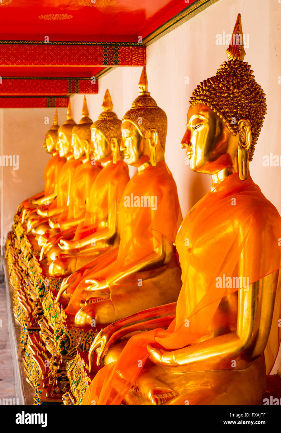 Fila di seduta statue di Buddha all'interno di Wat Pho o il Tempio del Buddha reclinato, Bangkok, Thailandia Foto Stock
