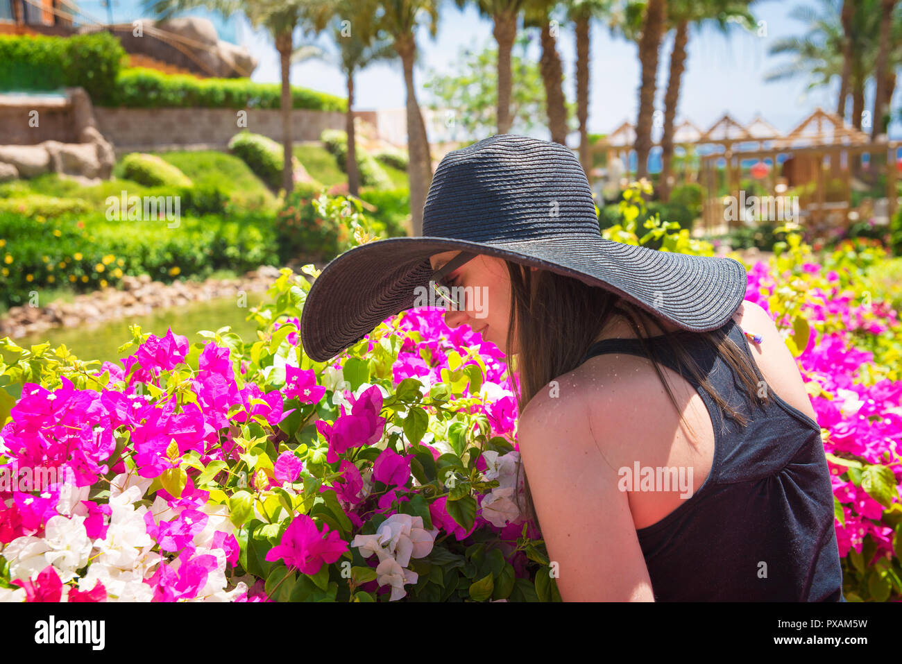 Donna odorare un fiore nel parco Foto Stock